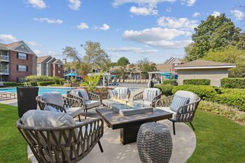 A patio with a table and chairs overlooking a pool.